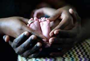 couple hands holding baby's tinny legs