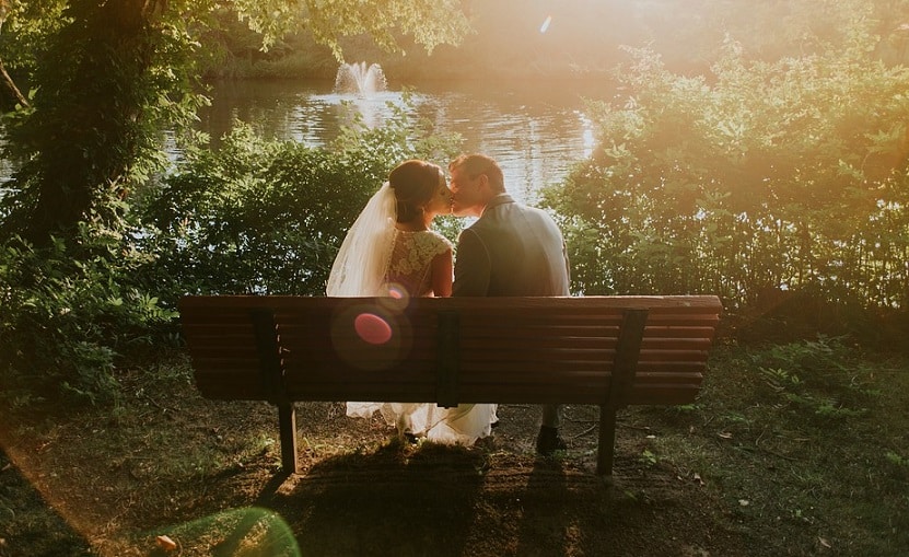 wedded couple kissing at sunset